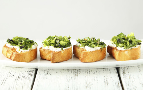Tasty fresh bruschetta on plate on white wooden background